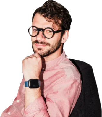 Man wearing glasses and a pink shirt resting his hand on his chin.