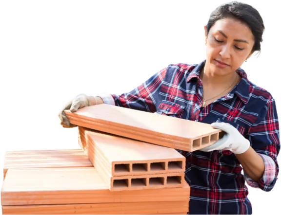 Woman in work gloves placing a block on a stack of bricks.