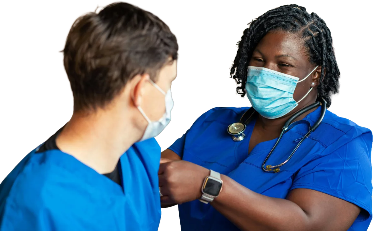 Masked clinician attending to a person in blue scrubs.