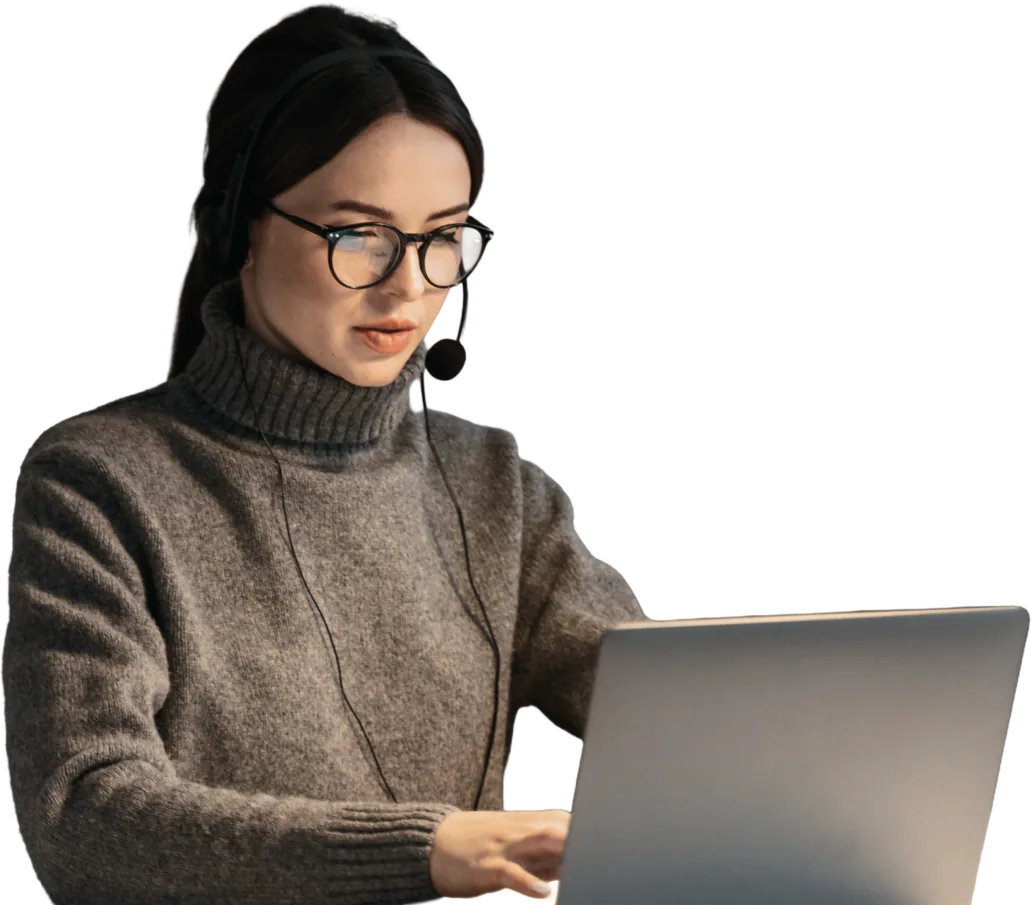 Woman wearing glasses and a headset working on a laptop.